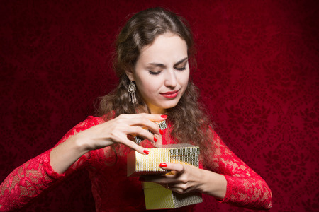 Beautiful girl dissatisfied with a small gift in a red dress. A gift for the new year, Christmas, birthday, Valentine's Dayの写真素材