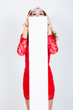 Girl in red dress and santa hat with blank white banners.の写真素材