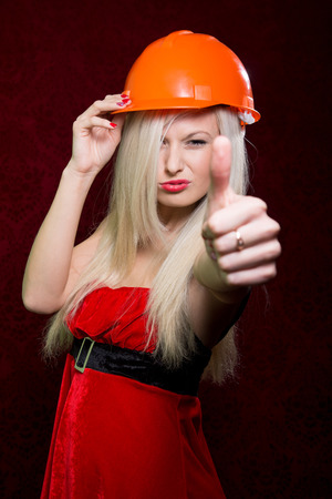 Portrait of a young girl in a Santa suit and helmet of the builder showing his thumb. positive signの写真素材