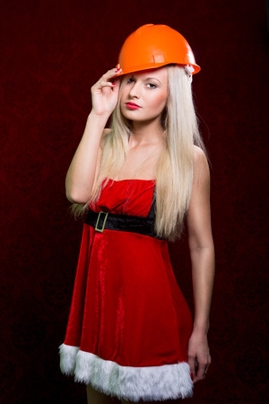 Portrait of a young girl in a Santa suit and helmet of the builder.の写真素材