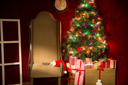 Christmas decor with fir tree and an armchair. Gifts at the Christmas tree. Horizontal image.の写真素材