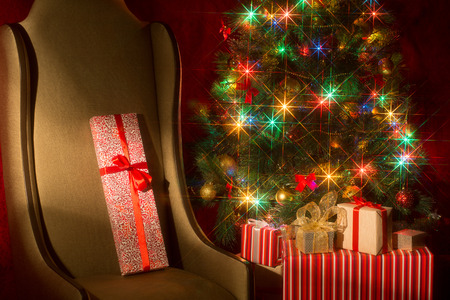 Christmas interior with illuminated Christmas tree and chair. Gifts at the Christmas tree. New Year's holiday. Spectacular nozzle with the starsの写真素材