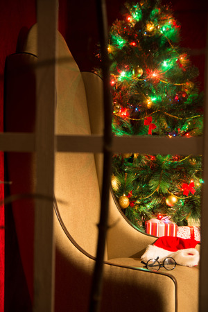 Christmas decor with fir tree and an armchair. Festive look out of the window into the room. vertical imageの写真素材