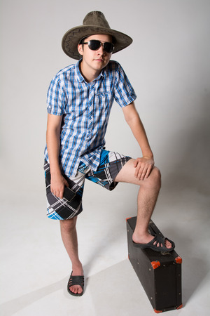 Portrait of young man in sunglasses with a suitcase. traveler in a hat with a phone in his hand.の写真素材