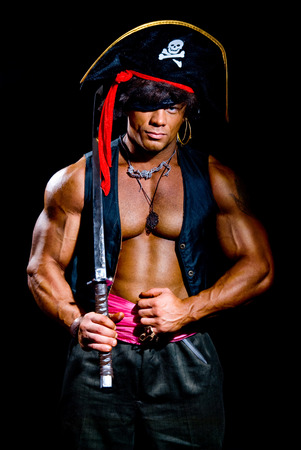 Muscular man in a pirate costume. Aggressive man with a sword on a black backgroundの写真素材