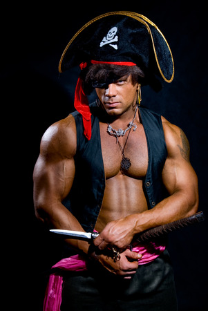 Portrait of a muscular pirate with a knife on a dark background. A man looking at the cameraの写真素材
