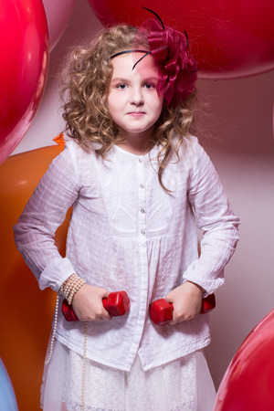 Teen girl with red dumbbells. Exercise, fitness on a background of large rubber ballsの写真素材