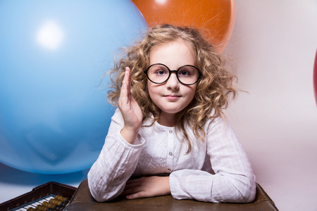 Portrait of a teenage schoolgirl with raised hand against the background of large rubber balls. Girl looking at the cameraの写真素材