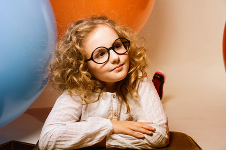 Portrait of curly teen girl in glasses on the background of large rubber balls. Girl looking to the side. toned imageの写真素材