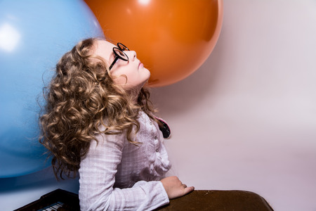 Portrait of curly teen girl in glasses on the background of large rubber balls. Girl looking upの写真素材
