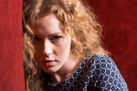 Closeup portrait of sad, depressed, stressed, thoughtful young woman, full of worries, looking at you, isolated on red . Human face expressions, emotions, feelings, reaction, attitudeの写真素材