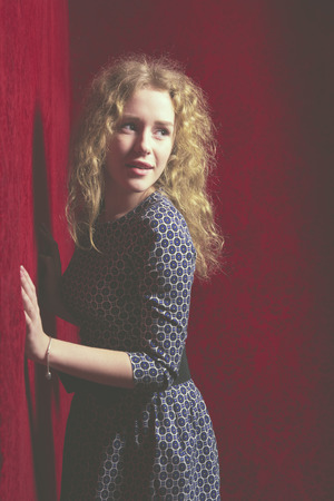 Thinking beautiful young woman looking to the side at red copyspace. Funky fresh and playful Caucasian smiling happy and joyful on red . toned imageの写真素材