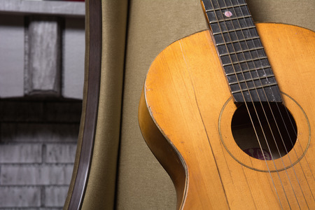 Close-up of acoustic guitar lying on the sofa against the brickworkの写真素材
