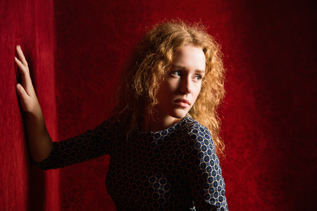 Portrait of sad, depressed, stressed, thoughtful young woman, full of worries, looking aside,  isolated on red background. Human face expressions, emotions, feelings, reactionの写真素材