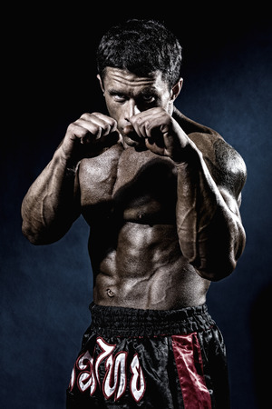 Fighter in a rack with fists. Portrait of a kick-boxer.の写真素材