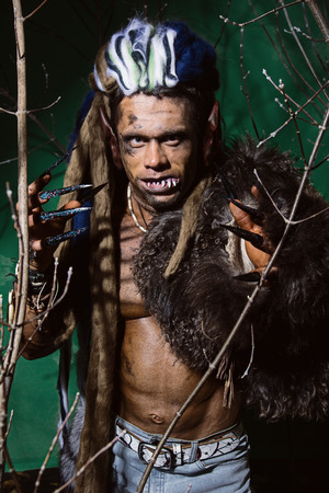 Werewolf with long nails and crooked teeth among the branches of the tree.の写真素材