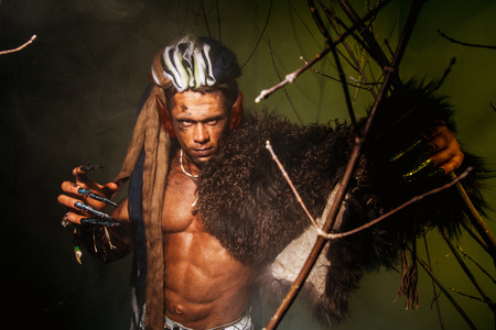 Werewolf with a skin on his shoulder and long nails among tree branches.の写真素材