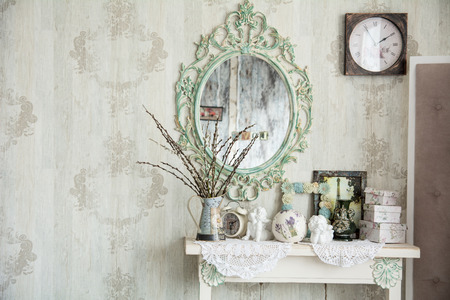 Vintage interior with mirror and a table with a vase and willows. Designer wall clock. Angels on the tableの写真素材