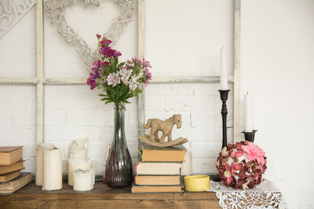 Interior with books, flowers and candles. Bright background with braided white heartの写真素材