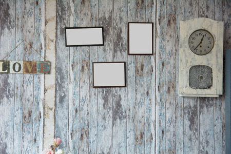 Empty frame on the background of the old wooden walls. The inscription on blackboard love and an old clockの写真素材