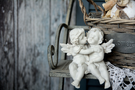 Figurines angels sitting on a bench. Romance on the background of old boardsの写真素材