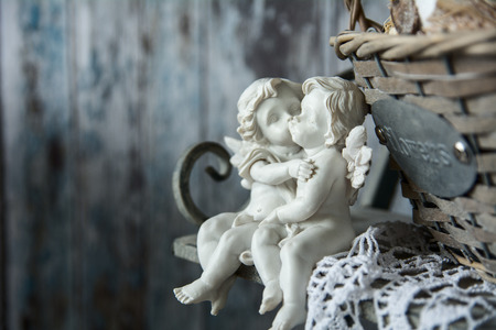 Figurines love angels sitting on a bench. Romance on the background of old boardsの写真素材