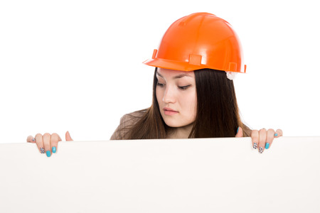 Girl builder in helmet looking at a blank banner. Asian young woman model displays ads. Isolated on a white backgroundの写真素材