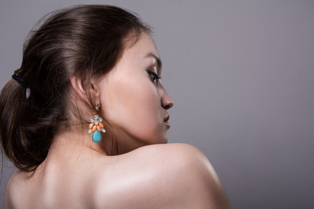 Close-up portrait of a girl with bare shoulders in profile on a gray backgroundの写真素材