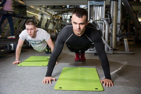 Two men working on exercise mat in fitness studio. Preparation of CrossFit, trainingの写真素材