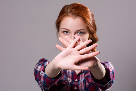 Out of focus woman with her hands signaling to stop isolated on a grey background.の写真素材