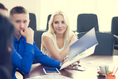 Young beautiful blonde business woman listening intently his colleagues.の写真素材