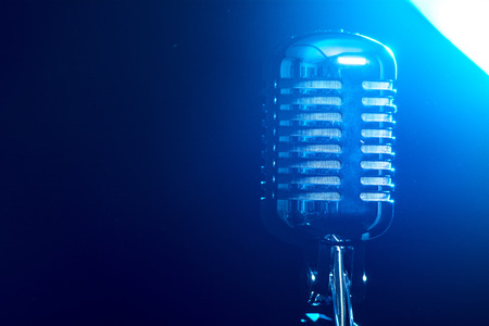 Metallic microphone isolated on a blue background.の写真素材