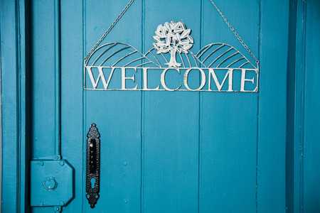 The inscription on the blue door welcome. Invitation to enter