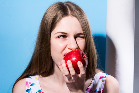 Close-up of a girl eating a red apple. Healthy food for a vegetarianの写真素材