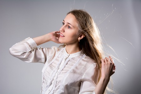 Beauty portrait of a young beautiful blonde girl with long straight flying hair. Magnificent hair.の写真素材