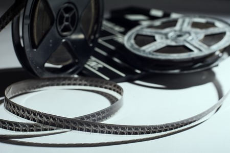 Old reel of film and cinema clap lying on a light. Twisted film strip on tableの写真素材