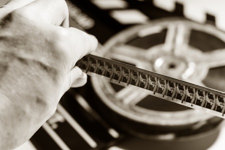 Close-up of film tape in hand on background of film roll and clap cinema. View film footageの写真素材