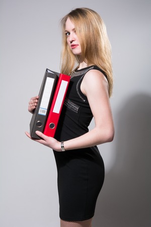 Young businesswoman holding folders isolated on a gray backgroundの写真素材
