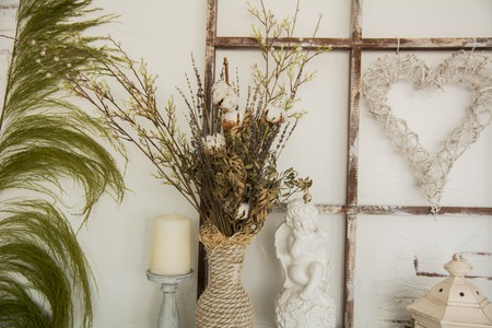 Vase with twigs, Ceramic angel, wicker heart of the branches and candle.