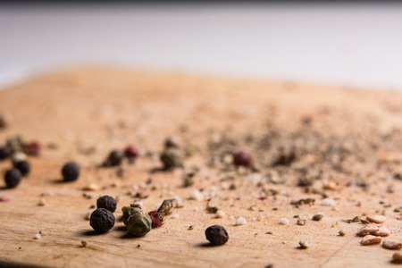 On a wooden board, ground pepper and peas. Close-up of a wooden background with black, green and red bell pepperの写真素材