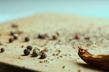 On a wooden board, ground pepper and peas. Close-up of a wooden background with black, green and red bell pepper and cayenne red pepperの写真素材