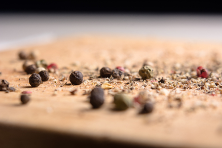 On a wooden board, ground pepper and peas. Close-up of a wooden background with black, green and red bell pepperの写真素材