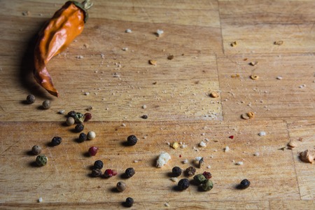 Background wooden cutting board with pepper. Top view of pepper scattered on the board. Dried red peppers in the kitchen.の写真素材