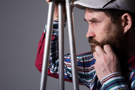 Man with beard a tripod thoughtfully looks aside