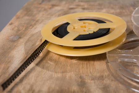Coil with 8 mm of film lies on a wooden surface. Plastic reels of celluloid filmの写真素材