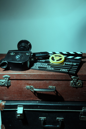 Old movie camera clapper and reel with film lie in two suitcasesの写真素材