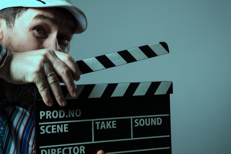 Close-up of a man smiling clapperboard cinema. Bearded man movie production of the comedy The assistantの写真素材