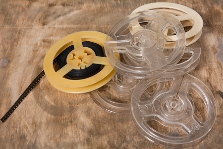 Coil with 8 mm of film lies on a wooden surface. Plastic reels of celluloid filmの写真素材
