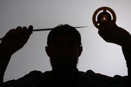 Silhouette of man looking on 8mm film strip.の写真素材
