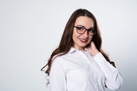 Close-up of smiling business woman in a white blouse. Young successful female holding glasses